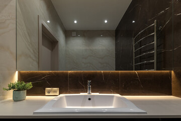 Sink close up. Light beige and brown modern bathroom interior with bath and shower and white...