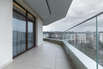 Large spacious balcony in a new house in rainy weather. Interior of a bright empty balcony in the house glass railings.