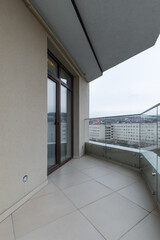 Large spacious balcony in a new house in rainy weather. Interior of a bright empty balcony in the house glass railings.