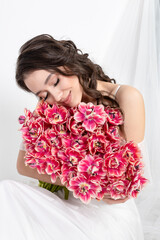 Sexy woman with flowers pink tulips in hands on a light background