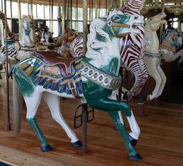 Fototapeta na wymiar Green and white carousel horse bedecked with saddle and tassels