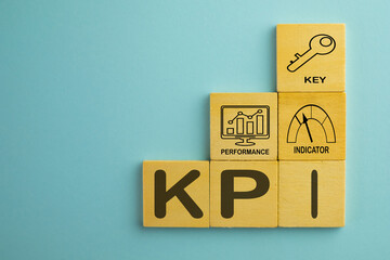 KPI or Key Performance Indicator use for business,finance Concept.,Word KPI and icon on wooden cube over blue background with copyspace.