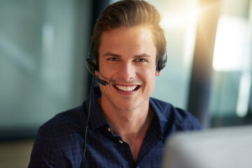 All about assisting the customer. Shot of a young male agent working in a call center.