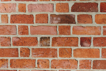 Textured red brick wall background or backdrop, rectangular red terracotta bricks laid out as pattern, architectural structure for old rough building