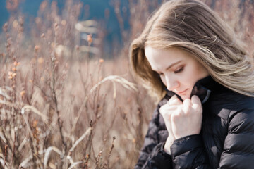 Young Beautiful Woman Thinking in Field Looking Down Wearing a Jacket