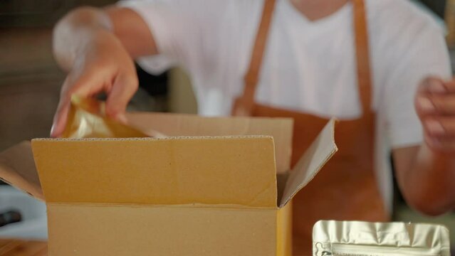 young man who owns a small coffee roaster and a young start-up is packing the finished coffee beans into bags and boxes.
