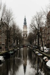 Obraz premium The Zuiderkerk (South Church) in Amsterdam reflected in a Amsterdam canal. Amsterdam houses line the canal and boats are in the canal.