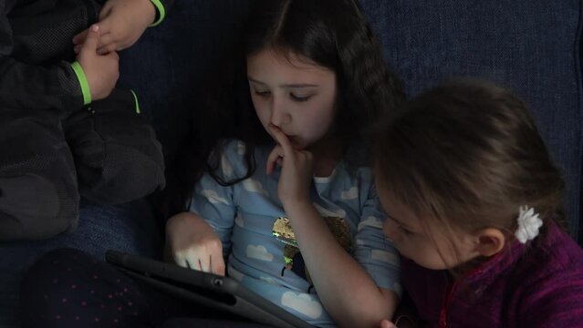 authentic 3 little preschool toddler minor children kids siblings watch cartoon playing games online chating on smartphone device laptop tablet together at home indoors. Family, childhood, friendship