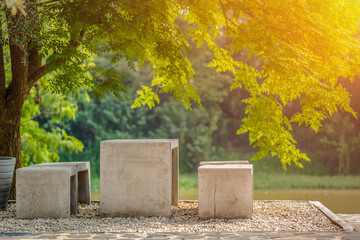 Naklejka premium Cement table and chairs under a tree against a blurred background.