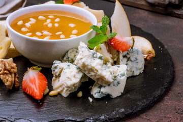 assorted European cheeses on black plate with honey