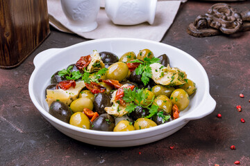 large olives with artichokes and sun-dried tomatoes on white plate