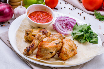 chicken kebab with tomato sauce and red onion on white plate