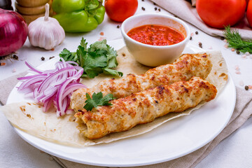 Lula kebab chicken with tomato sauce on white plate