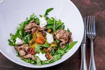 Salad with roast beef and poached egg on white plate