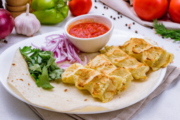 Lula kebab from potatoes with tomato sauce on white plate