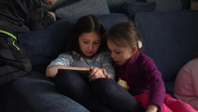 authentic 3 little preschool toddler minor children kids siblings watch cartoon playing games online chating on smartphone device laptop tablet together at home indoors. Family, childhood, friendship