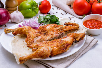 fried chicken tobacco with tomato sauce and red onion on white plate