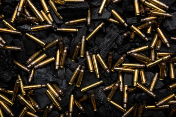Empty shells from weapons on black smoldering coals. Consequences of the war. Dark back.