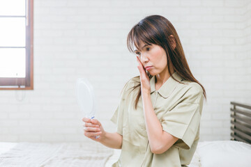 鏡を見るミドル世代の女性（困る）
