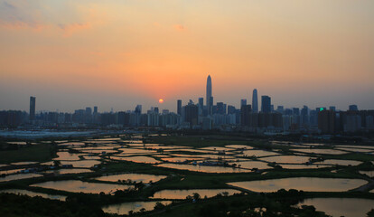 Shenzhen skyline , with skyscrapers and office against fish farm or fish ponds, during dramatic moment in evening, from the view of boundary of Hong Kong suburb where is named Ma Tao Lung