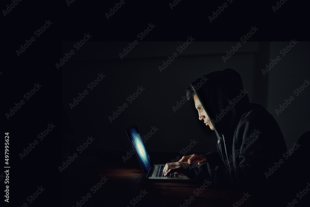 Aufkleber helping himself to your passwords. shot of a hooded computer hacker using a laptop in the dark.