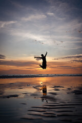 Silhouette of man Jumping on Beach at Sunset