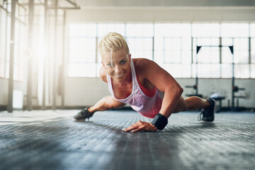 Excuses dont burn calories. Shot of a young attractive woman doing push ups with one hand at the...