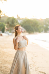 Woman in glamorous long skirt on wind, posing on the beach. Summer Holiday.