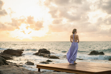 Woman in purple dress on the beach, enjoy sunset romantic moment.