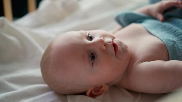 Little cute causian baby boy, smiling at camera, the boy lies on his back and turns