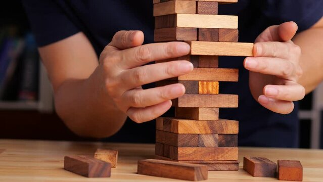 Building wood blocks tower on table, high risk assessment. Risk assessment concept.
