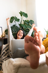 Excited young caucasian woman raising arms up celebrating success at home using laptop. Copy space....