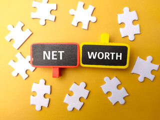 Top view white puzzle with text NET WORTH on a yellow background.