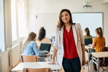 Happy computer science teacher in the classroom looking at camera.