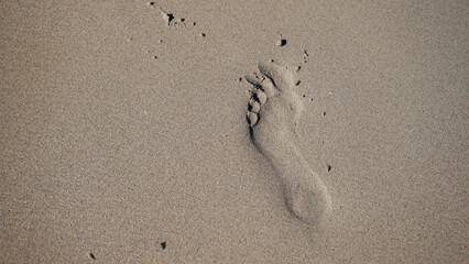 Footprints in the sand washed away by the sea waves on the beach