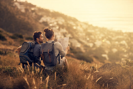 Youll never regret a day outdoors. Rearview shot of a couple looking at a map while taking a break from hiking.