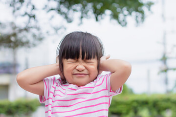 Portrait image of 4-5 years old kid. Close her ears and eyes.