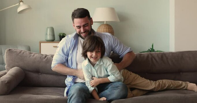 Laughing man and little preschool son spend funny active leisure on weekend together, loving dad tickling his adorable cheerful 5s child. Family bonding, playtime at home with children, fun concept