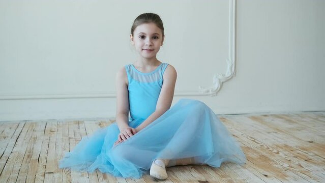 School of ballet. Little ballerina is sitting on the floor.