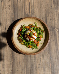 Salad with burrata cheese and tomatoes on a plate on wooden table top view