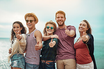 Thumbs up to lifelong friends. Portrait of a group of friends showing thumbs up outside.