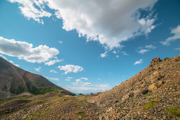 Scenic landscape with sunlit mountain pass under clouds in blue sky in sunny day. Colorful mountain...