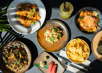 Different foods on the table including pasta, sushi, poke, passion fruit mojito, guacamole etc