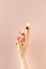 A mockup of a cosmetic bottle with a facial serum in a woman's hand.