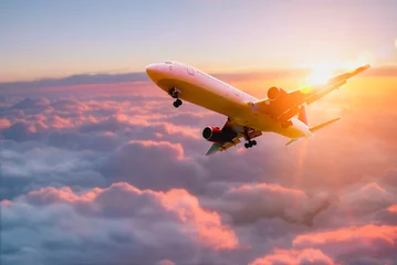 Poster Passagiers vliegtuig. Passagiers commerciële vliegtuig vliegen boven wolken in zonsondergang licht. Zakenreis. Commercieel vliegtuig. Concept van snel reizen, vakanties en zaken. © Panya Studio