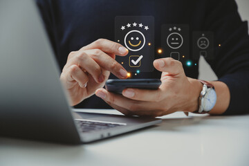 Customer satisfaction concept, Young man using smartphone check mark icon face emoticon smiley for evaluate product and service.
