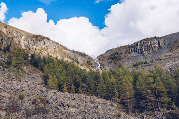 Picturesque waterfall among the rocks in the mountains in the distance. Amazing mountains and forest scenic view. Blue sky with white clouds landscape stock photography