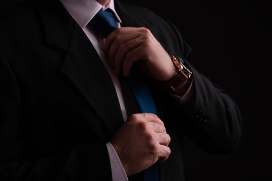 man with hand on tie in suit with watch on wrist