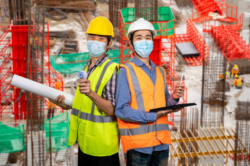 Two young asian engineers wearing surgical mask with tablet and blueprint isolated on white background. New normal concept. (With clipping path)