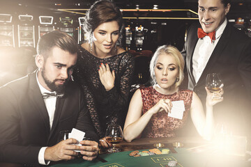 Group of young rich people playing poker in the casino